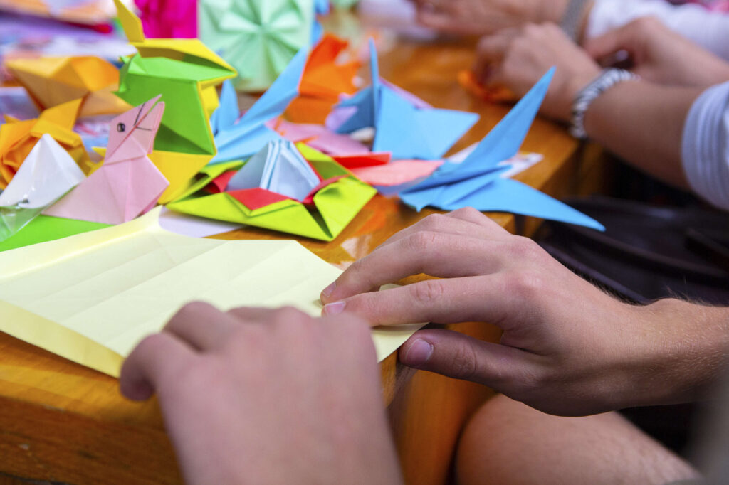 Hands of a man creating a colored origami paper